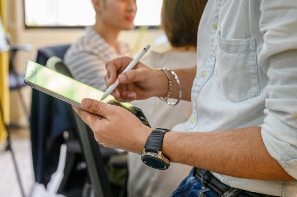 Close-up of a person using a stylus to write on an iPad in a modern office environment.